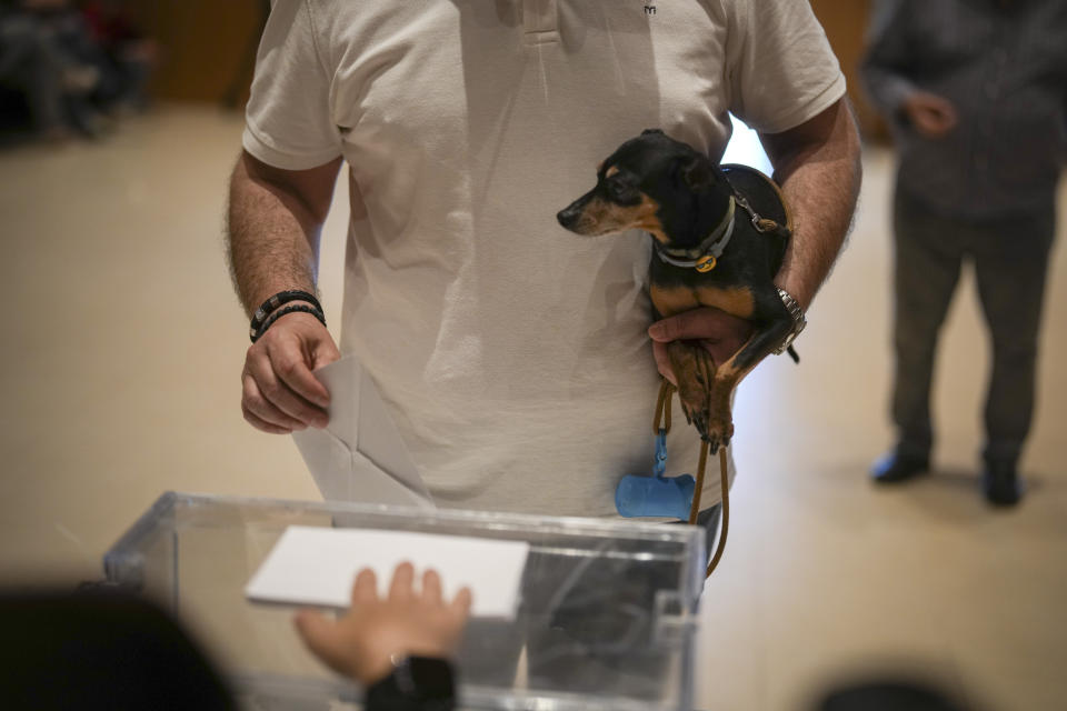 A voter holds his puppy as he casts his ballot for Catalonia's regional elections in La Roca del Vallès, north of Barcelona, Sunday May 12, 2024. About 6 million Catalans are casting ballots in a regional election that will test if Catalonia wants pro-independence leader Carles Puigdemont back or if the wealthy region has moved on to more pressing worries.(AP Photo/Emilio Morenatti)