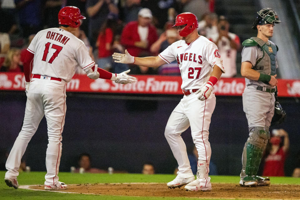 Los Angeles Angels' Shohei Ohtani, left, celebrates with Mike Trout, center, after Trout's solo home run with Oakland Athletics catcher Sean Murphy looking away during the fourth inning of a baseball game in Anaheim, Calif., Wednesday, Sept. 28, 2022. (AP Photo/Alex Gallardo)