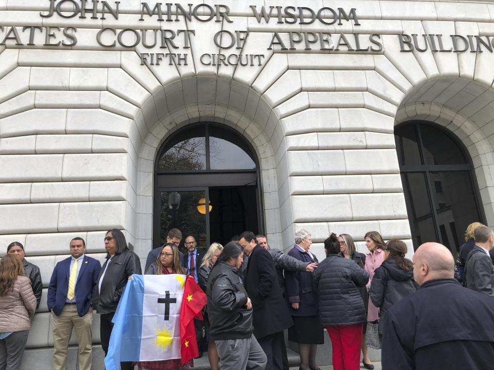 FILE - Rosa Soto Alvarez, of Tucson, Ariz., holds a flag of the Pascua Yaqui Tribe as she and other Native Americans stand outside the federal appeals court in New Orleans, Jan. 22, 2020. The Supreme Court on Thursday, June 15, 2023, preserved the 1978 Indian Child Welfare Act, which gives preference to Native American families in foster care and adoption proceedings of Native children, rejecting a broad attack from Republican-led states and white families who argued it is based on race. (AP Photo/Kevin McGill, File)