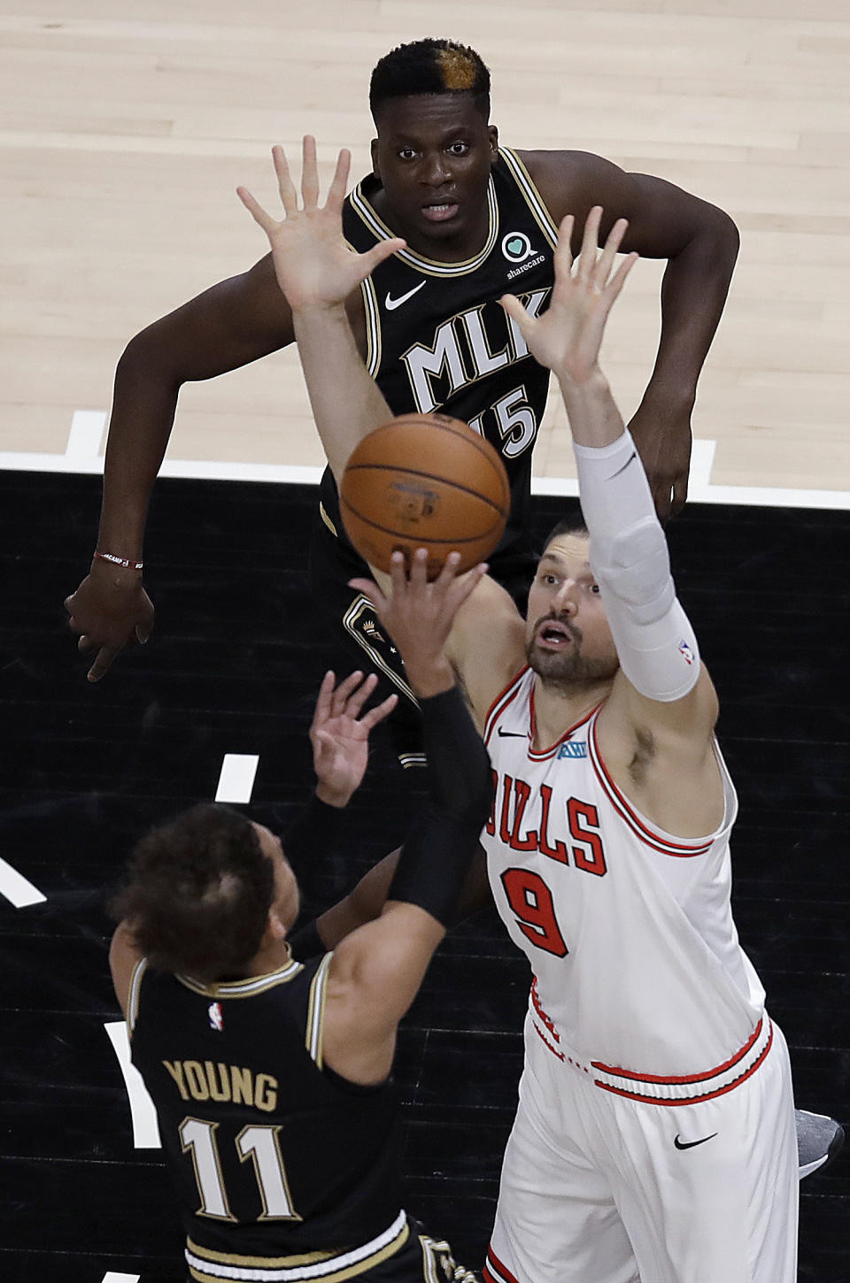 Chicago Bulls' Nikola Vucevic (9) defends against the shot of Atlanta Hawks' Trae Young (11) during the first half of an NBA basketball game Friday, April 9, 2021, in Atlanta. (AP Photo/Ben Margot)