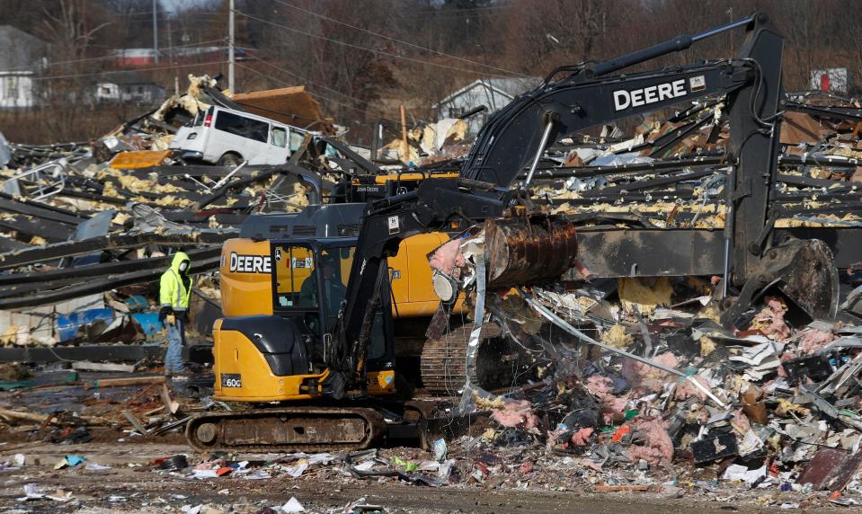 People look around the candle factory where workers were killed when a tornado struck Friday evening.Dec. 11, 2021