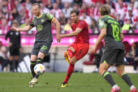 Bayern's Leon Goretzka, centre, kicks the ball ahead of Wolfsburg's Maximilian Arnold during the German Bundesliga soccer match between Bayern Munich and VfL Wolfsburg at the Allianz Arena in Munich, Germany, Sunday, May 12, 2024. (AP Photo/Matthias Schrader)