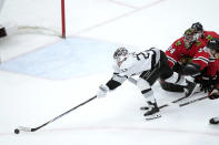 Los Angeles Kings' Kevin Fiala, left, is unable to get control of the puck as he skates past Chicago Blackhawks goaltender Petr Mrazek (34) during the second period of an NHL hockey game Friday, March 15, 2024, in Chicago. (AP Photo/Charles Rex Arbogast)