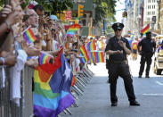 FILE - A police officer applauds as parade-goers shout and wave flags during the New York City Pride Parade, Sunday, June 26, 2016 in New York. As Pride weekend approaches, the recent decision by organizers of New York City's event to ban LGBTQ police officers from marching in future parades while wearing their uniforms has put a spotlight on issues of identity and belonging, power and marginalization. (AP Photo/Mel Evans, File)