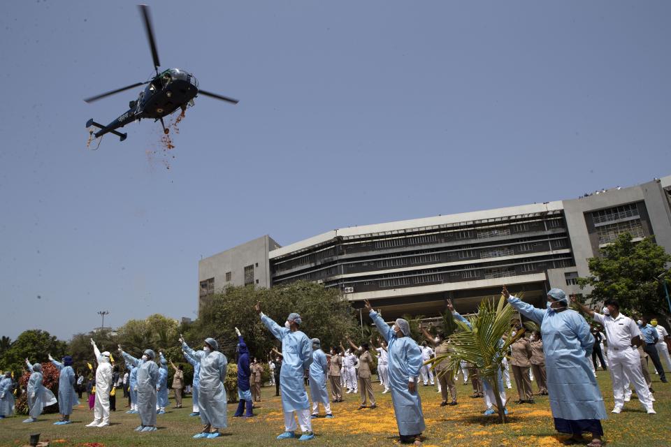 An Indian Air Force helicopter showers flower petals on the staff of INS Asvini hospital in Mumbai, India, Sunday, May 3, 2020. The event was part the Armed Forces' efforts to thank the workers, including doctors, nurses and police personnel, who have been at the forefront of the country's battle against the COVID-19 pandemic. (AP Photo/Rajanish Kakade)