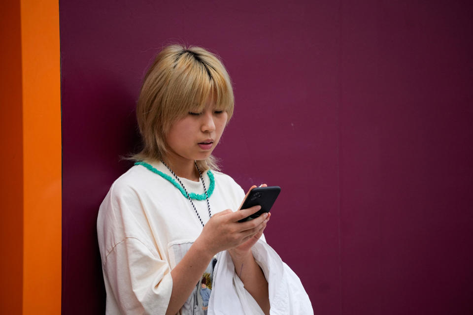 A woman looks at an Apple iPhone on a street, in Shanghai, China September 27, 2023. REUTERS/Aly Song