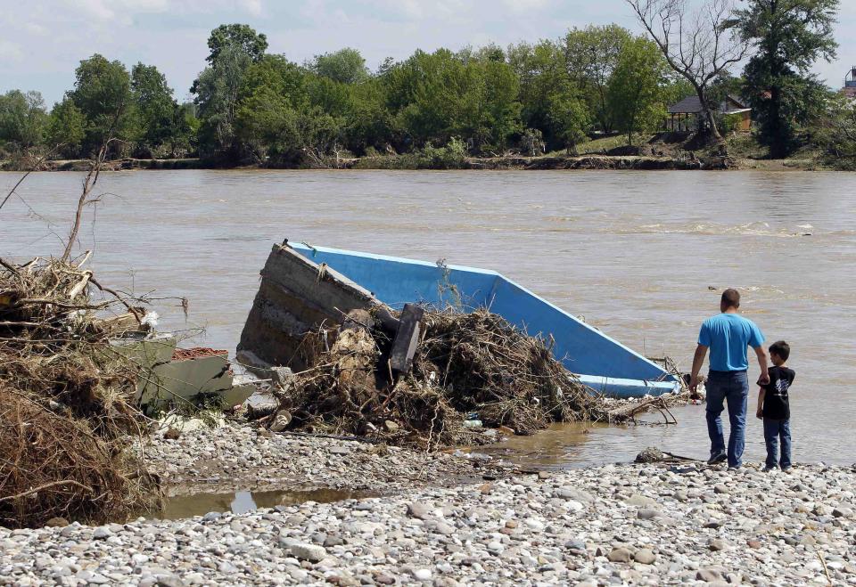 A man and his son look at a wrecked swimming pool on the bank of river Bosna after heavy floods in Odzak