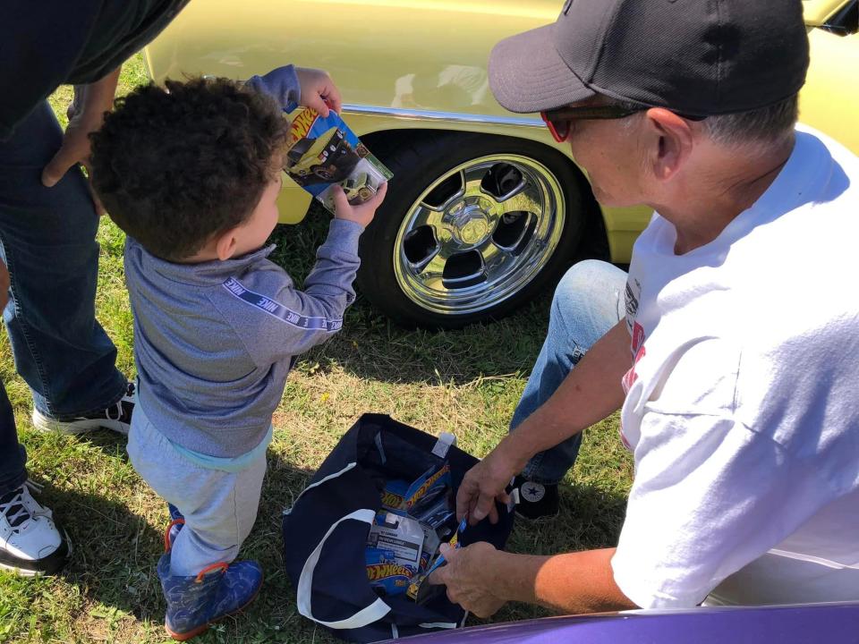 Ron Gelster of Chesterfield let two-year-old Keith Bresko pick out a Hot Wheels toy at Old School Hot Rodders of Virginia Spring Cruise In in Sutherland on May 6, 2023.