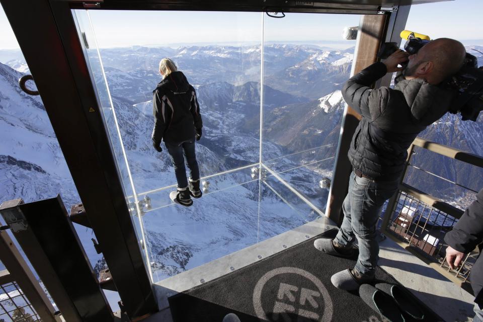 Journalists and employees stand in the 'Step into the Void' installation during a press visit at the Aiguille du Midi mountain peak above Chamonix, in the French Alps