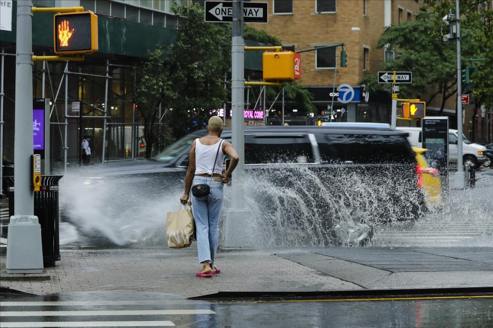 A pedestrian avoids being splashed by passing automobiles during heavy rain brought by Tropical Storm Fay, Friday, July 10, 2020, in New York. Beaches closed in Delaware and rain lashed the New Jersey shore as fast-moving Tropical Storm Fay churned north on a path expected to soak the New York City region. (AP Photo/Frank Franklin II)