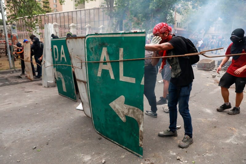 Manifestantes se protegen con un escudo improvisado durante las protestas contra el gobierno en Chile