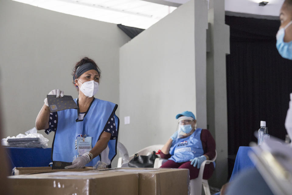 Electoral officials wearing protective masks as a precaution against the spread of the new coronavirus, count ballots after polls closed during the presidential elections, in Santo Domingo, Dominican Republic, Sunday, July 5, 2020. (AP Photo/Tatiana Fernandez)