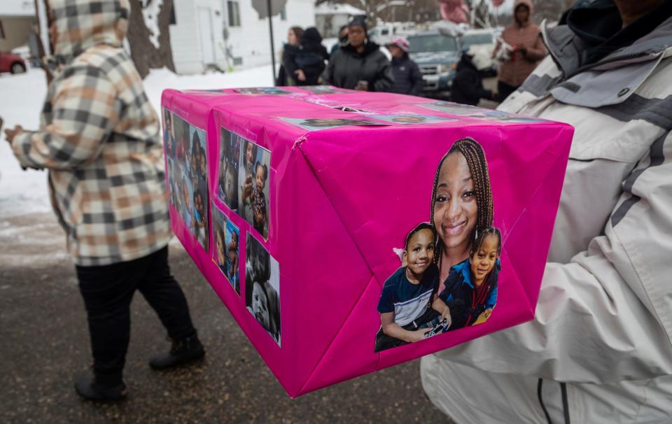 Rhodesia Cannady holds a pink box decorated with photos of Monica and her children during a vigil in Pontiac on Sunday, Jan. 29, 2023. Cannady and her two children died of hypothermia in Pontiac after they slept in a field.