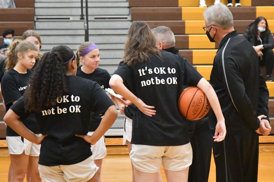 Delran coach Pete Miles and his team listen to a pregame talk with an official before their game against Burlington Township