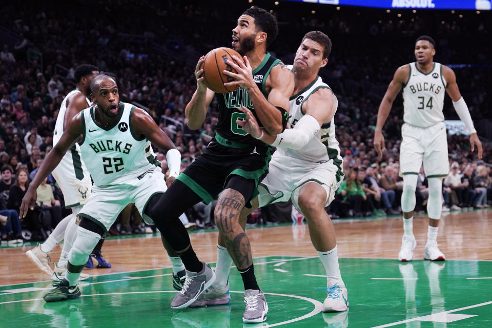 Boston Celtics forward Jayson Tatum drives to the basket against Milwaukee Bucks center Brook Lopez, right, and forward Khris Middleton (22) during the first half of an NBA basketball game, Wednesday, Nov. 22, 2023, in Boston. (AP Photo/Charles Krupa)