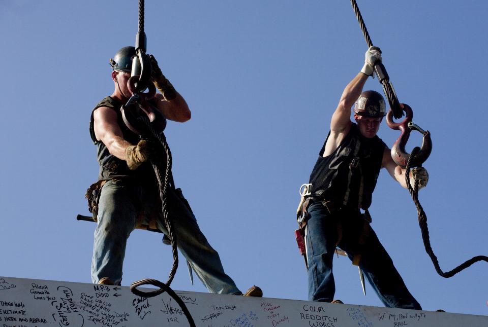 Ironworkers James Brady, left, and Billy Geoghan release the cables from a steel beam after connecting it on the 104th floor of 1 World Trade Center, Thursday, Aug. 2, 2012 in New York. The beam was signed by President Barack Obama with the notes: "We remember," ''We rebuild" and "We come back stronger!" during a ceremony at the construction site June 14. Since then the beam has been adorned with the autographs of workers and police officers at the site. The beam will be sealed into the structure of the tower, which is scheduled for completion in 2014. (AP Photo/Mark Lennihan)