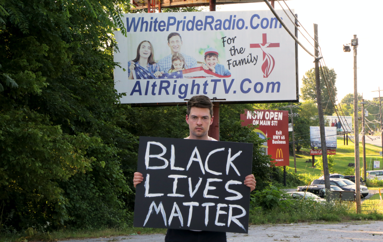 Rob Bliss stands in front of a white pride sign in Harrison, Ark., where he filmed himself facing harassment while holding a Black Lives Matter sign. (Rob Bliss)