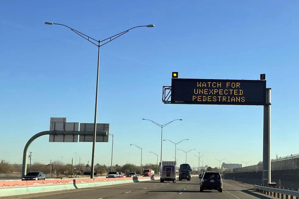 An electronic sign flashes "Watch for unexpected pedestrians," Tuesday, Dec. 20, 2022, on the highway next to the fenced US-Mexican border just east of downtown El Paso, Texas, next to one of the three bridges that connect the Texas city with the sprawling metropolis of Juarez, Mexico. Many migrant advocates expect Juarez to "empty out" if Title 42 is lifted, since thousands of migrants have been biding their time there, waiting for a chance to cross into the United States without being immediately sent back. (AP Photo/Giovanna Dell'Orto)