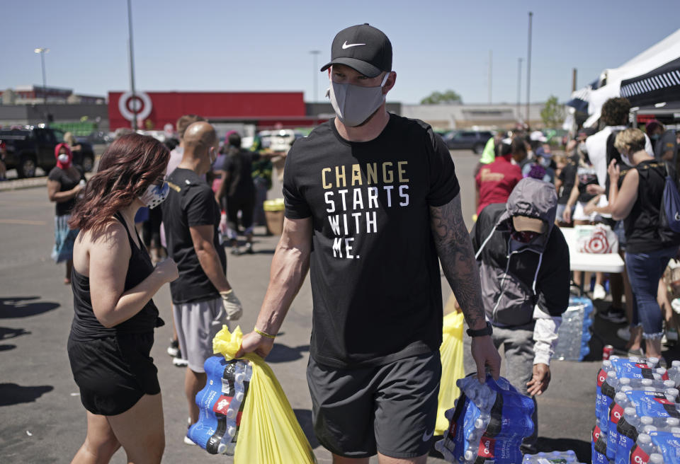 In this photo taken Friday, June 5, 2020, Minnesota Vikings NFL football player Kyle Rudolph helps a woman carry items to her car at the "Change Starts with Me" food and household supply giveaway outside a Cub Foods store in Minneapolis. George Floyd was killed less than three miles from the stadium where the Minnesota Vikings play, so this global unrest over racial relations and justice hit awfully close to home for the team. (Brian Peterson/Star Tribune via AP)