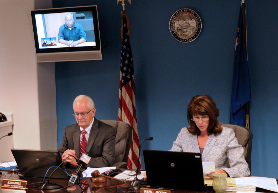 O.J. Simpson, in custody at the Lovelock Correctional Center, is on the video screen above Nevada Board of Parole hearing representative Robin Bates, left, and Commissioner Susan Jackson during a video conference parole hearing, in Carson City, Nev., on Thursday, July 25, 2013. O.J. Simpson pleaded for leniency Thursday, telling the parole panel he deeply regretted robbing two sports memorabilia dealers. (AP Photo/Nevada Appeal, Geoff Dornan)