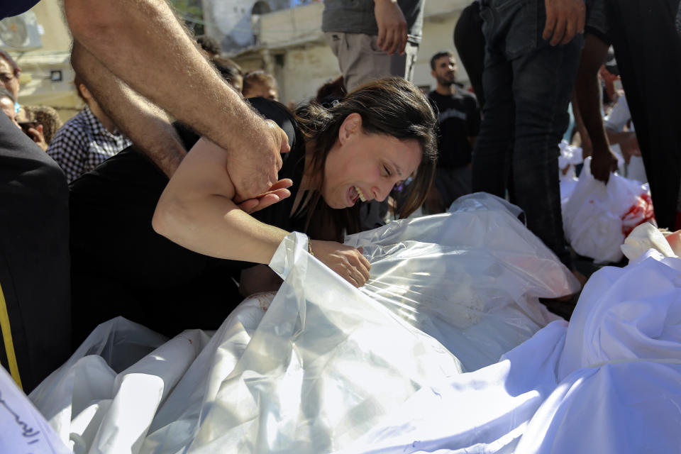 FILE - A Palestinian woman mourns over the bodies of her relatives who were killed in Israeli airstrikes that hit a Greek Orthodox church, in Gaza City, Friday, Oct. 20, 2023. Palestinians say the devastating war between Israel and Hamas is robbing them not only of their loved ones but also of the funeral rites that long have offered mourners some dignity and closure in the midst of grief. (AP Photo/Abed Khaled, File)