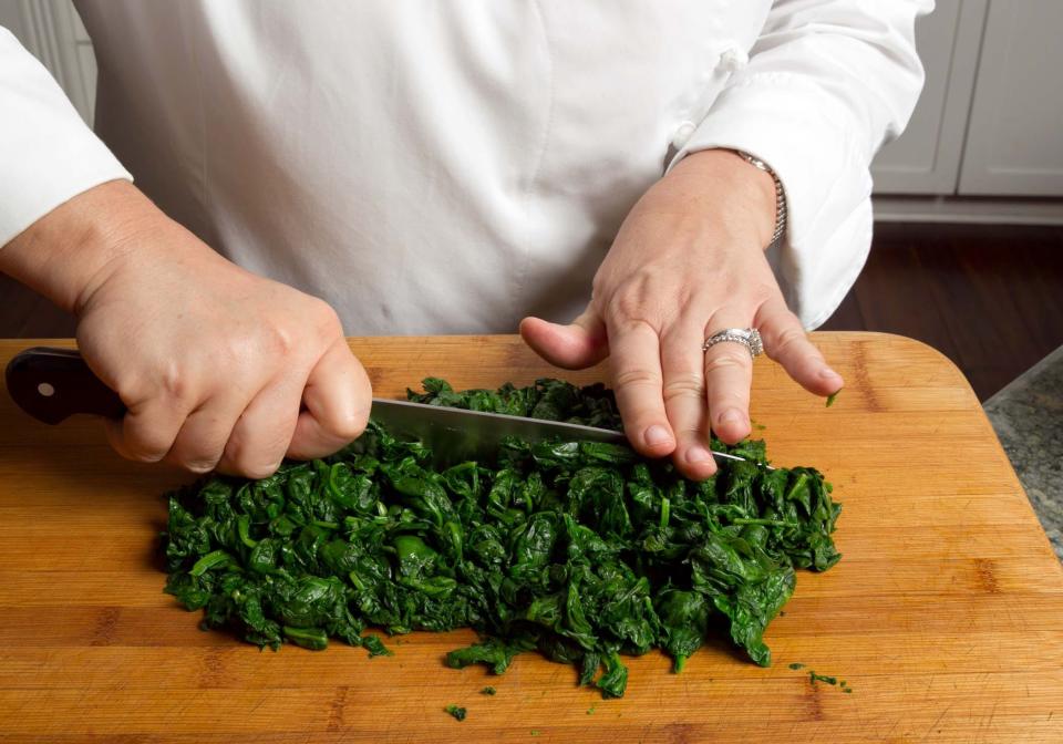 Once blanched, wrap the spinach in a tea towel and wring out liquid before chopping it.