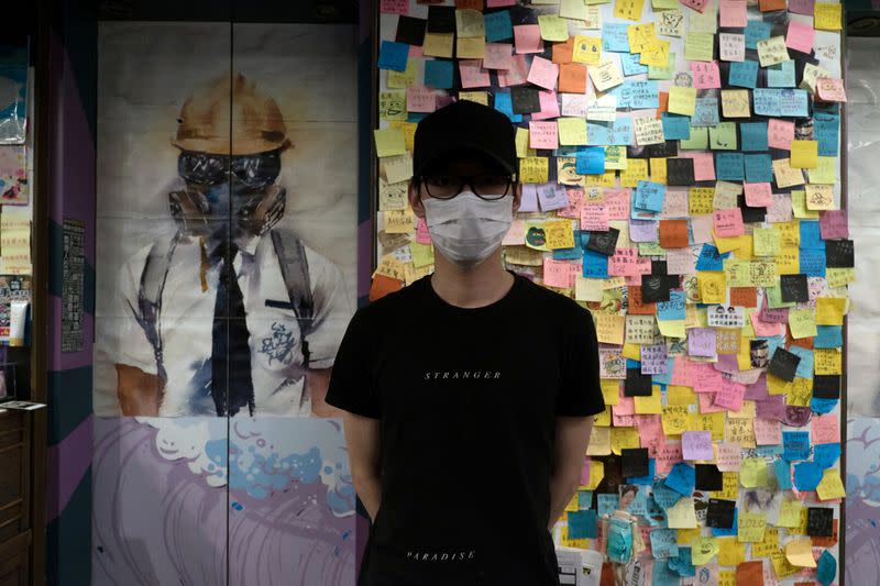 KC, owner of Mainichi restaurant, poses for a photo in front of a "Lennon Wall" in Hong Kong