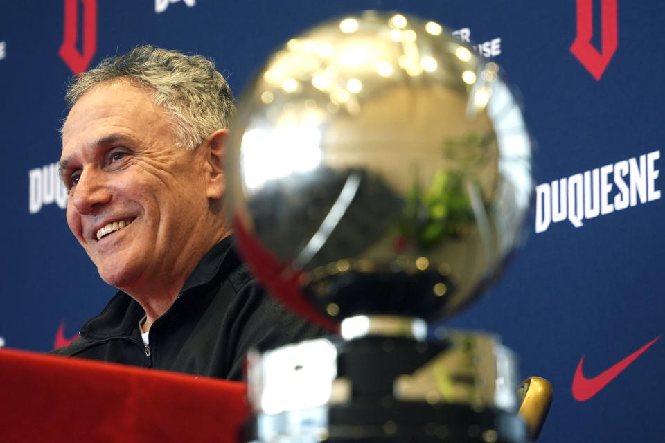 Duquesne University men's basketball coach Keith Dambrot sits next to the Atlantic 10 Championship trophy during a gathering in Pittsburgh celebrating Duquesne earning a berth in the NCAA Men's Basketball Tournament for the first time since 1977 Monday, March 18, 2024. Dambrot announced that he is retiring after his team's NCAA tournament run. (AP Photo/Gene J. Puskar)