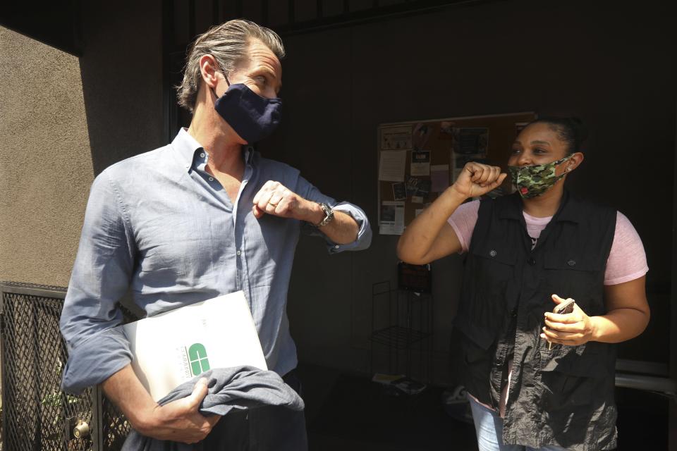 California Gov. Gavin Newsom prepares to connect elbows with Candace O'Connor, owner of Brimberry Barber and Beauty Salon, in Leimert Park in Los Angeles after she shared her thoughts on running a business in the time of COVID-19 and the recent protests in the city Wednesday, June 3, 2020. (Genaro Molina/Los Angeles Times via AP, Pool)