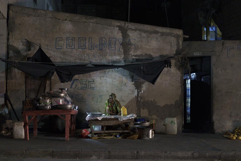 A street food vendor looks on as she waits for a client in Saint Louis, Senegal, Friday, Jan. 20, 2023. Officials promised the drilling in the area would soon bring thousands of jobs and diversification of the economy. Instead, residents say, the rig has brought only a wave of problems, unemployment and more poverty. (AP Photo/Leo Correa)