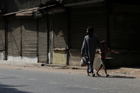 A man and a boy walk along a market with closed shops during a protest, after the Supreme Court overturned the conviction of a Christian woman sentenced to death for blasphemy against Islam, in Karachi, Pakistan November 2, 2018. REUTERS/Akhtar Soomro