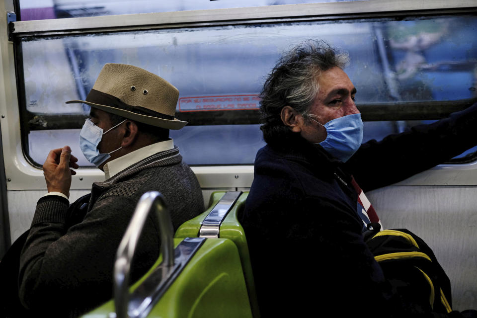 Commuters wear face masks, which were distributed by authorities at the Pantitlan metro station, in Mexico City, Friday, April 17, 2020. Authorities announced that starting Friday, it is mandatory to wear a mask when riding trains, to prevent the spread of the new coronavirus. (AP Photo/Fernando Llano)