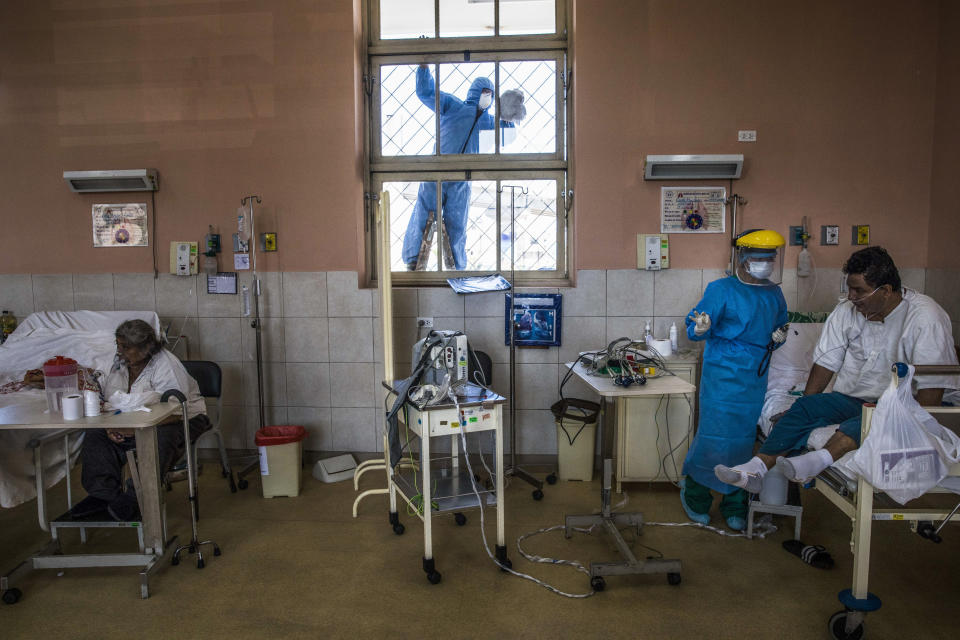 Un trabajador con equipo protector limpia el vidrio de una ventana de la unidad de cuidados intensivos del Hospital 2 de Mayo de Lima el 17 de abril del 2020. (AP Photo/Rodrigo Abd)