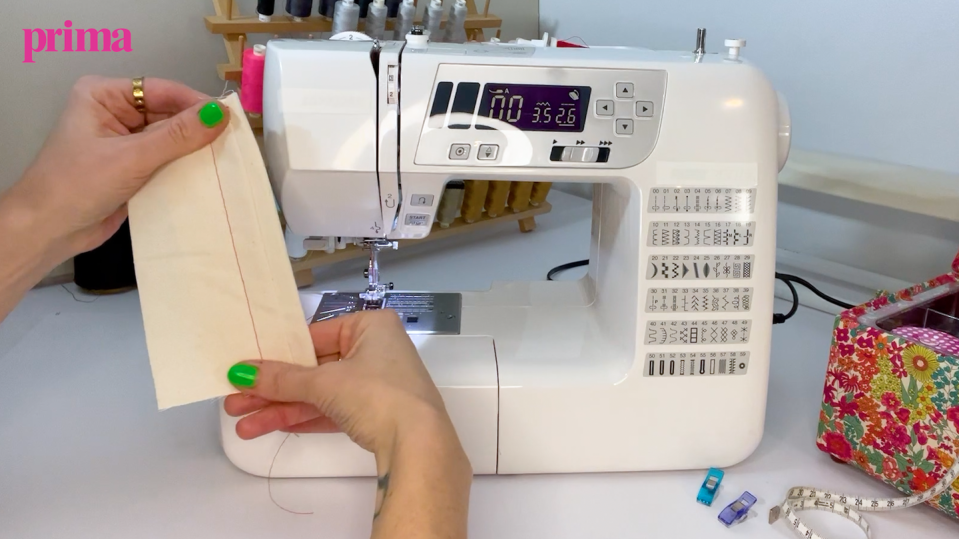 hands holding up fabric in front of a sewing machine