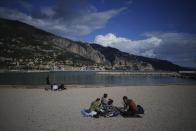 Tourists enjoy the sun on the beach in Menton, France, Wednesday, March 6, 2024. The mild climate — from a protective mountain range, proximity to the sea and steady sunshine with moderate rain during winter months — and sandstone-rich soil give the Menton lemon its distinct flavor. (AP Photo/Daniel Cole)