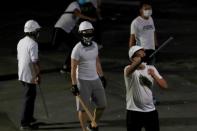 Men in white T-shirts with poles are seen in Yuen Long after attacked anti-extradition bill demonstrators at a train station, in Hong Kong