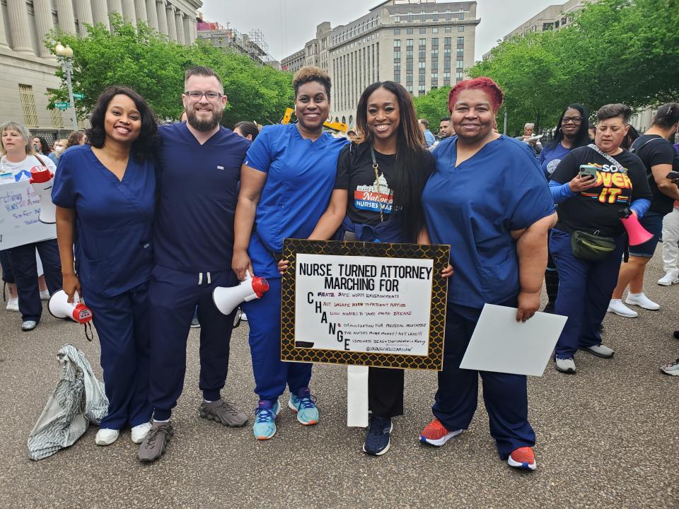 Five rallygoers in blue nurses' scrubs at a protest.