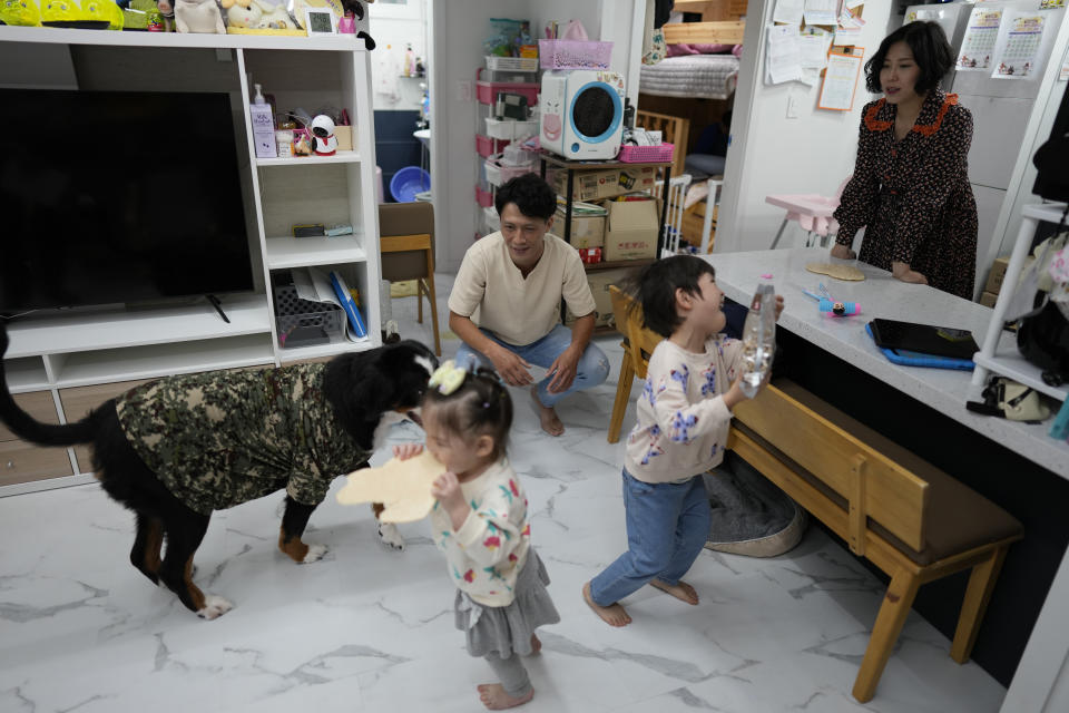 Seo Ji Seong, right, her husband Kim Dong Uk, their children and a dog are seen after an interview at their home in Anyang, South Korea, Sunday, Oct. 9, 2022. Many young people in South Korea have chosen not to marry or have children, citing a change of views toward a marriage and family life and uncertainty of their future. (AP Photo/Lee Jin-man)