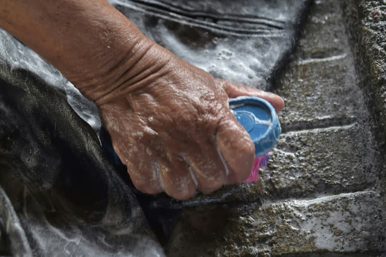 Washerwomen rub dirty clothes against rough stones at an old public laundry in Quito