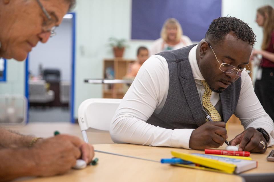 Right, Curtis Clark, board president of the Boys & Girls Clubs of the Coastal Bend, draws on a stone for a community garden, funded by Humana and built by the club, on Thursday, June 9, 2022, in Corpus Christi, Texas.