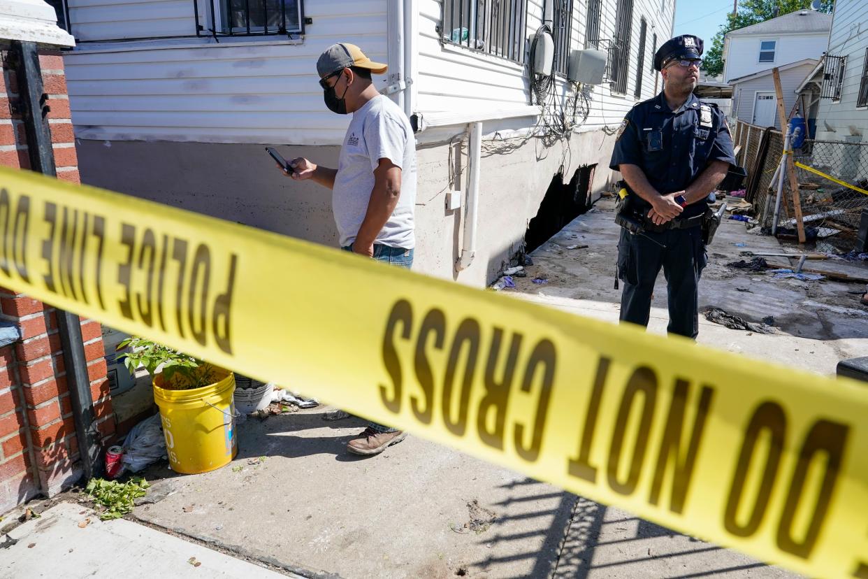 A police officer stands guard as a man survey the damage to home where people died after their basement apartment flooded in the Jamaica neighborhood of the Queens borough of New York, Thursday, Sept. 2, 2021, in New York.