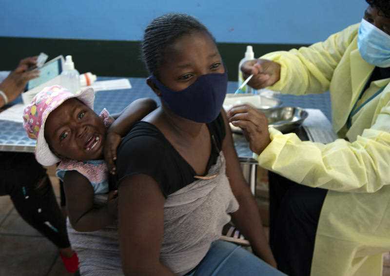 A baby cries as her mother receives her Pfizer vaccine against COVID-19, in Diepsloot Township near Johannesburg