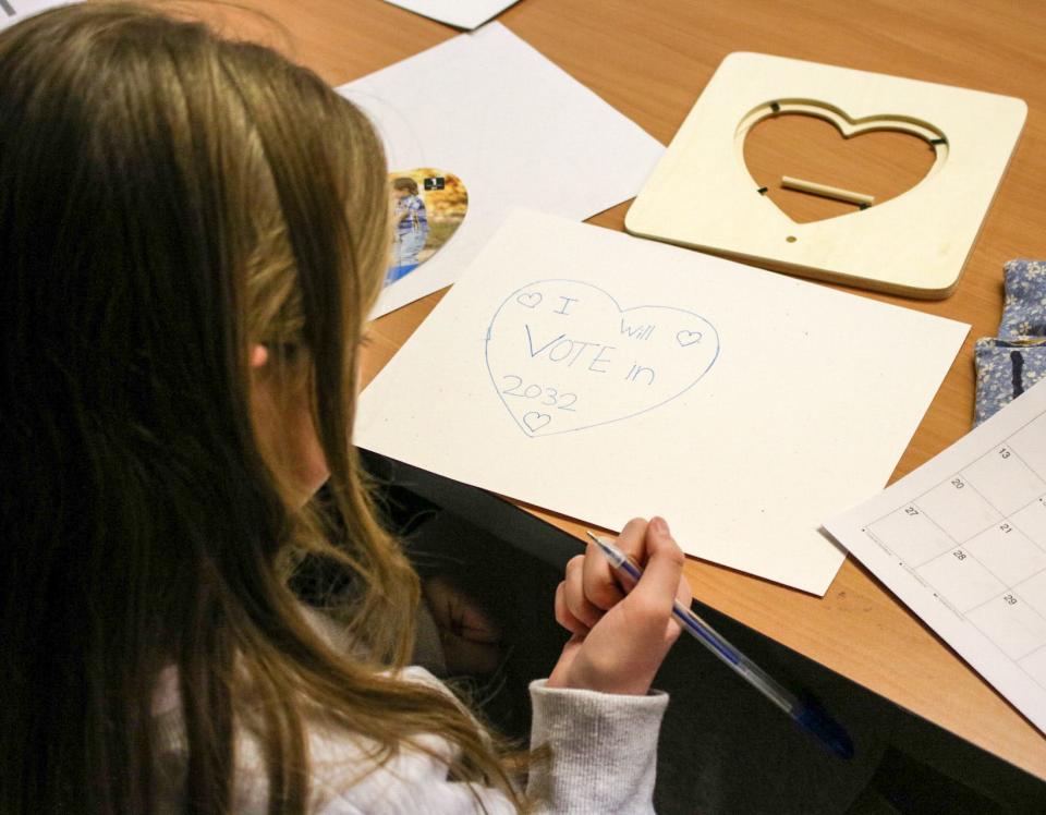 Ainsley Zies, 11, of Hutchinson, Kansas, works on a framed illustration of the first year she will be able to vote. Her heart-shaped illustration reads "I will vote in 2032."