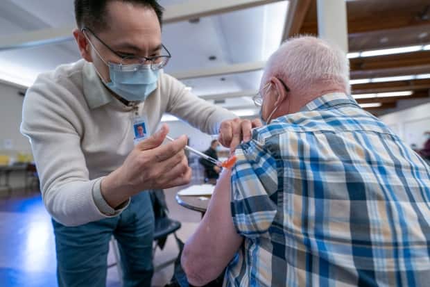 Dr. E. Kwok administers a COVID-19 vaccine to a recipient at a vaccination clinic run by Vancouver Coastal Health, in Richmond, B.C., in April 2021.  (Jonathan Hayward/Canadian Press - image credit)