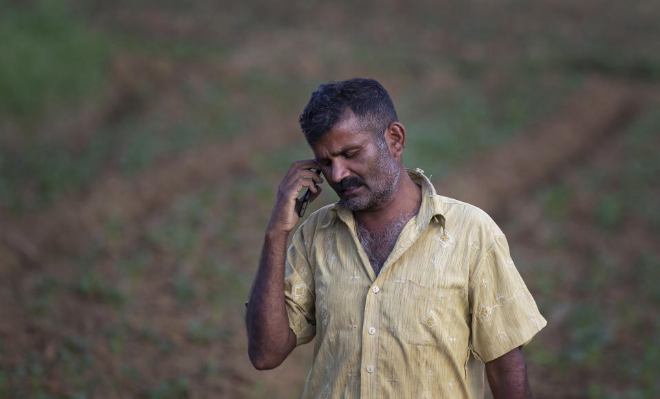 Sri Lankan potato farmer Pathmasiri Kumara speaks over his mobile phone as he checks the availability of fertilizer in the market in Keppetipola, Sri Lanka on July 1, 2021. Sri Lanka has cut back on imports of farm chemicals, cars and even its staple spice turmeric as its foreign exchange reserves dwindle, hindering its ability to repay a mountain of debt as the South Asian island nation struggles to recover from the pandemic. (AP Photo/Eranga Jayawardena)