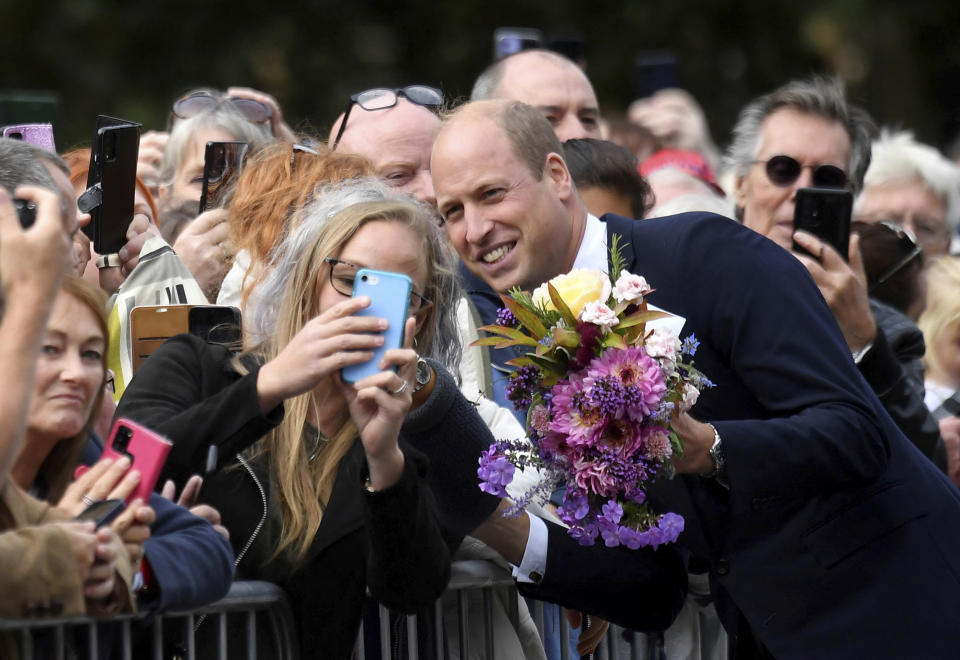 Britain's William, Prince of Wales poses for a photo with a well-wisher as he and Kate, Princess of Wales view floral tributes left by members of the public, in memory of late Queen Elizabeth II, at the Sandringham Estate, in Norfolk, England, Thursday, Sept. 15, 2022. Queen Elizabeth II, Britain's longest-reigning monarch died Thursday Sept. 8, 2022, after 70 years on the throne. (Toby Melville/Pool via AP)