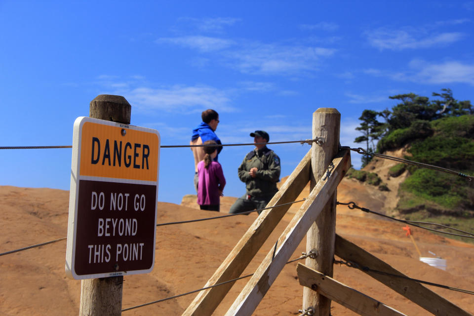 A park ranger with the Oregon Parks and Recreation Department talks to a man and his daughter who walked through the fence at Cape Kiwanda State Natural Area in Cloverdale, Oregon, June 29, 2016. / Credit: Zach Urness/Statesman-Journal via AP