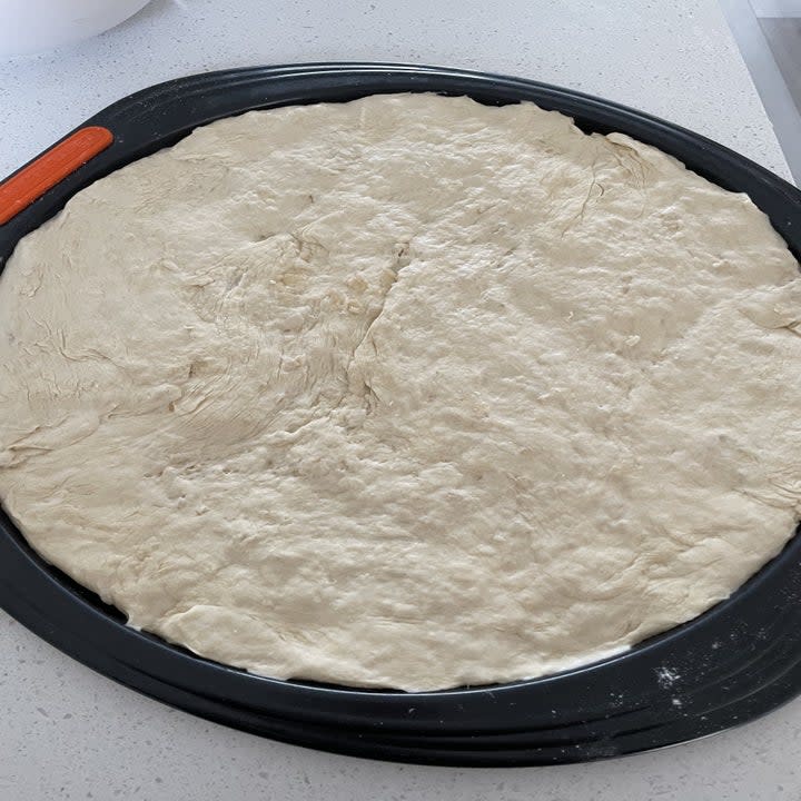 raw pizza dough on a pizza pan