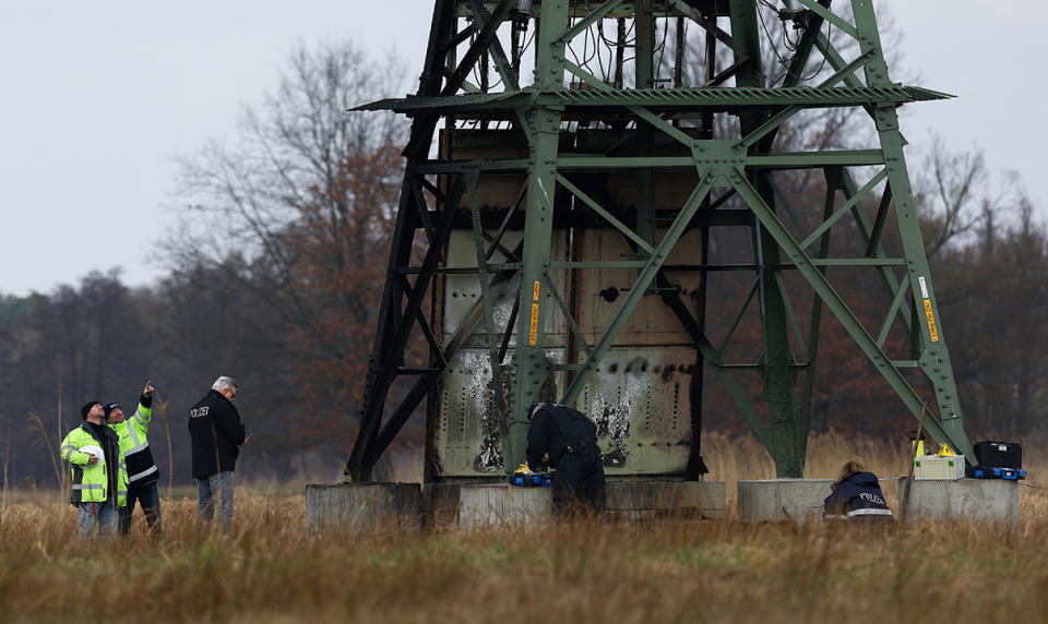 Workers repair an electricity pylon that was set ablaze near Tesla's Gigafactory