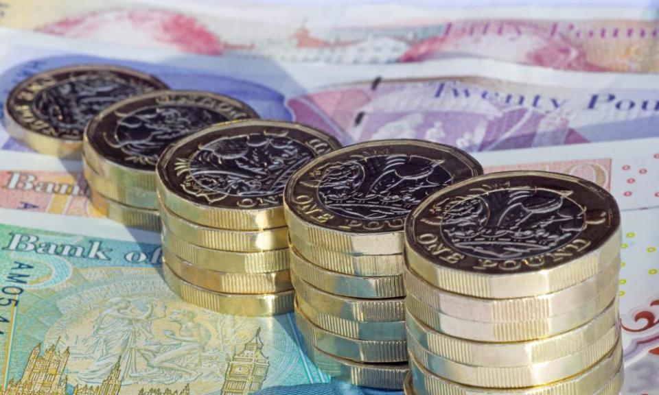 Stacks of one pound coins on British pound notes.